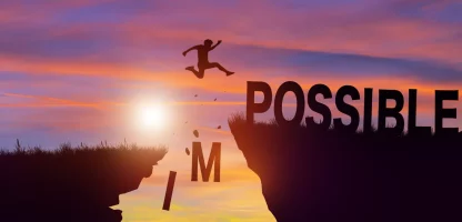Person jumping between two rocks as the word 'Impossible' changes to 'Possible' with the 'IM' falling away.