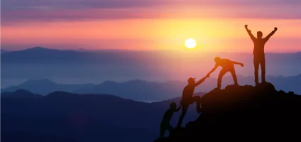 Group of climbers helping each other up a mountain, with one person at the top raising their arms in victory.